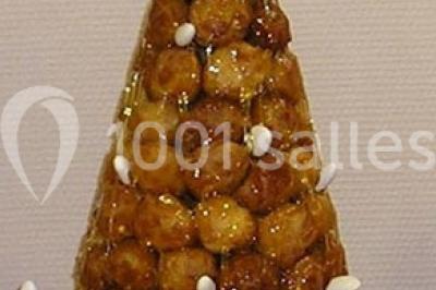 Miniature Traiteur Lezoux (Puy-de-Dôme) - Deneuville Traiteur #22 Pyramide de macarons colorés surmontée de figurines de mariés, présentée sur une table rouge en extérieur.