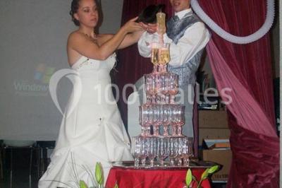 Miniature Traiteur Lezoux (Puy-de-Dôme) - Deneuville Traiteur #23 Pyramide de macarons colorés surmontée de figurines de mariés, présentée sur une table rouge en extérieur.