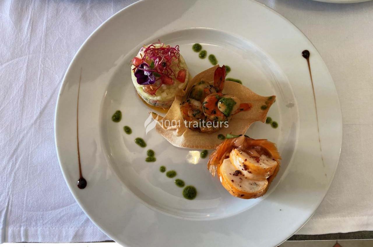 Assiette gastronomique composée de trois préparations raffinées, décorée de sauces et présentée sur une nappe blanche.