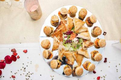 Table élégamment dressée avec bougies décoratives, serviettes pliées, verres en cristal et chemin de table sombre.