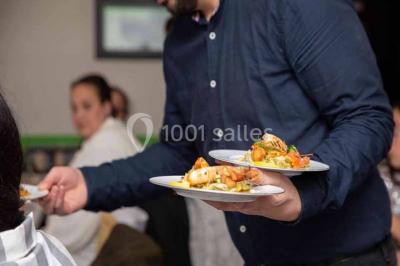 Table élégamment dressée avec bougies décoratives, serviettes pliées, verres en cristal et chemin de table sombre.