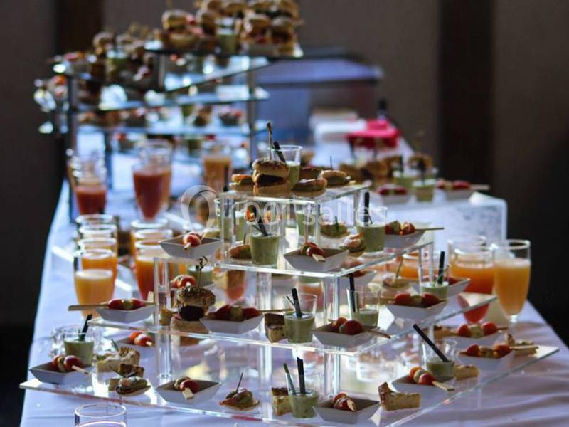 Buffet avec verrines, mini-sandwichs et jus de fruits disposés sur des présentoirs en verre et métal.