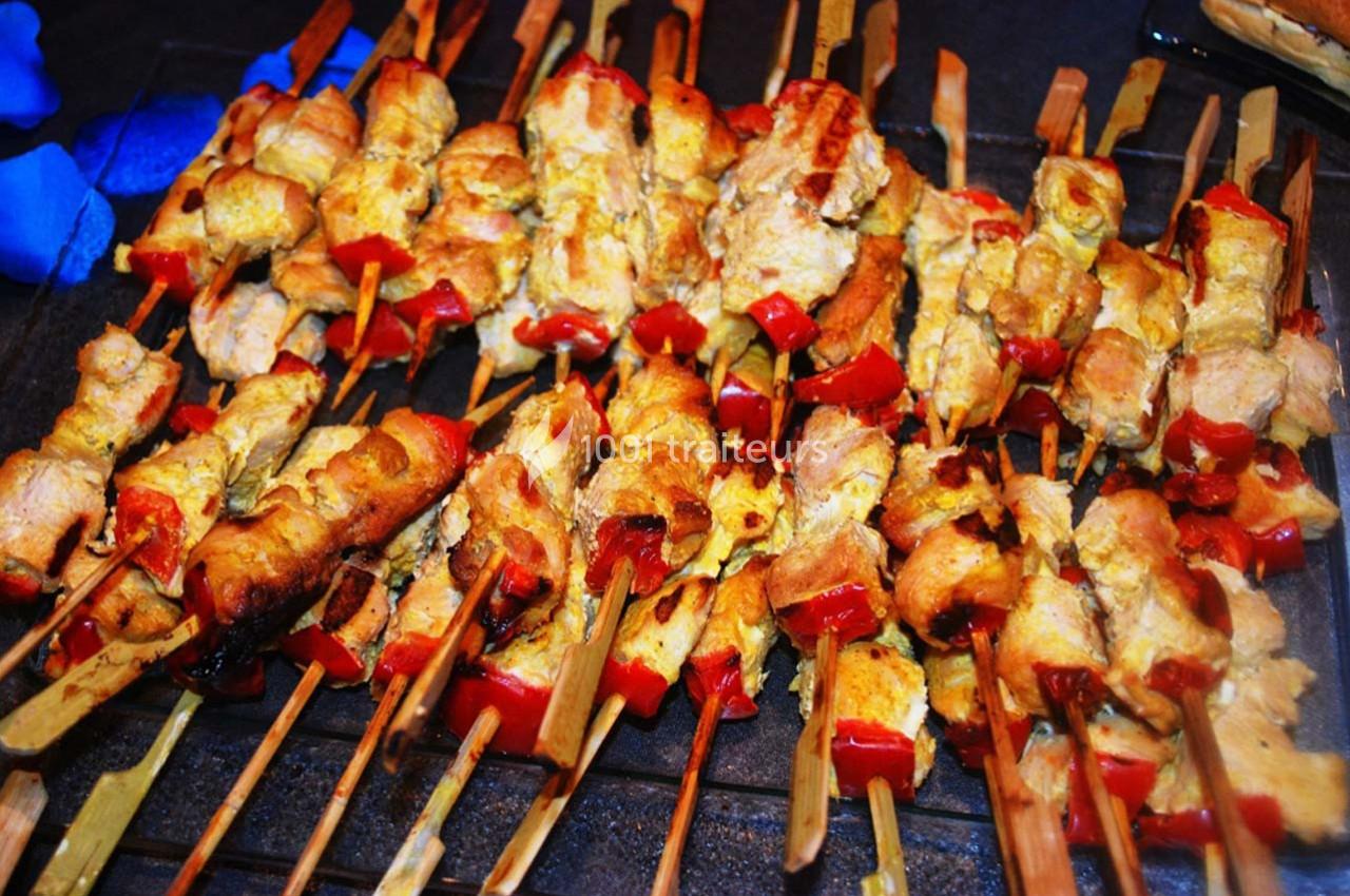 Brochettes de viande grillées avec morceaux de poivrons rouges, disposées sur un plateau.