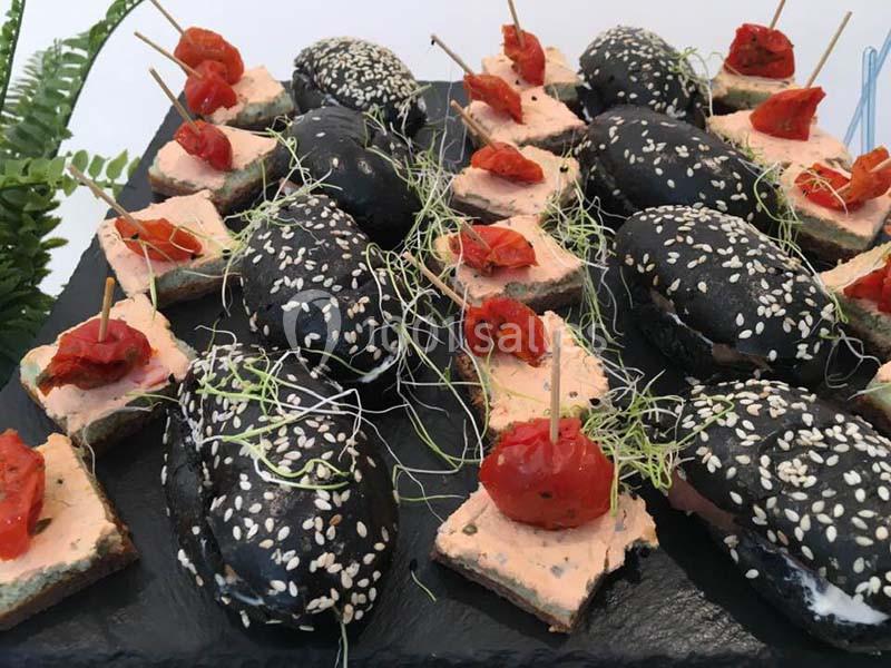 Assortiment de mini-burgers au pain noir et canapés garnis de foie gras, tomates confites et pousses vertes.