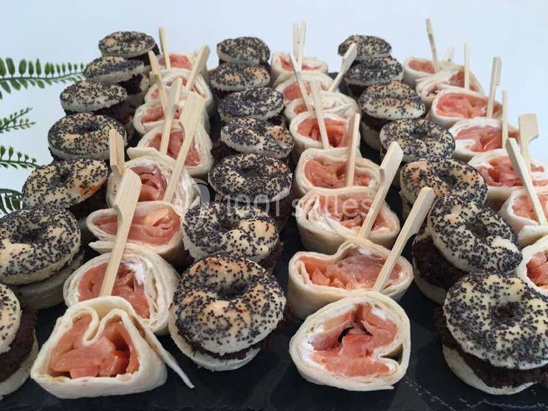 Plateau de mini-bagels au pavot et roulés de saumon fumé, présentés avec des piques en bois.