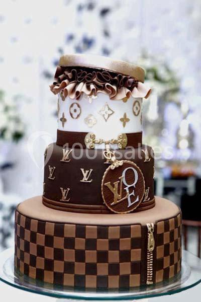 Gâteau à étages décoré de motifs luxueux, avec des détails en chocolat et des ornements dorés.