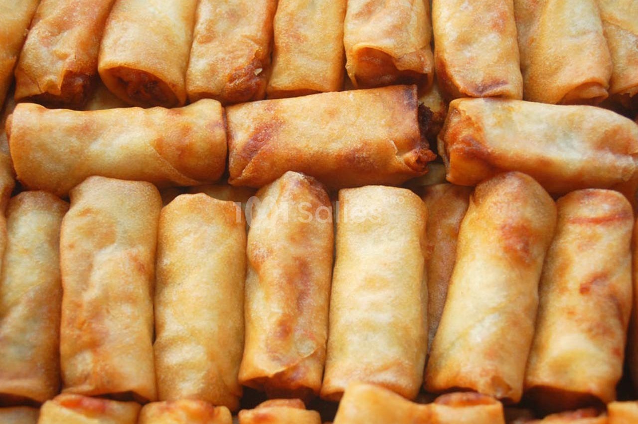 Rouleaux de printemps frits dorés alignés en rangées serrées.