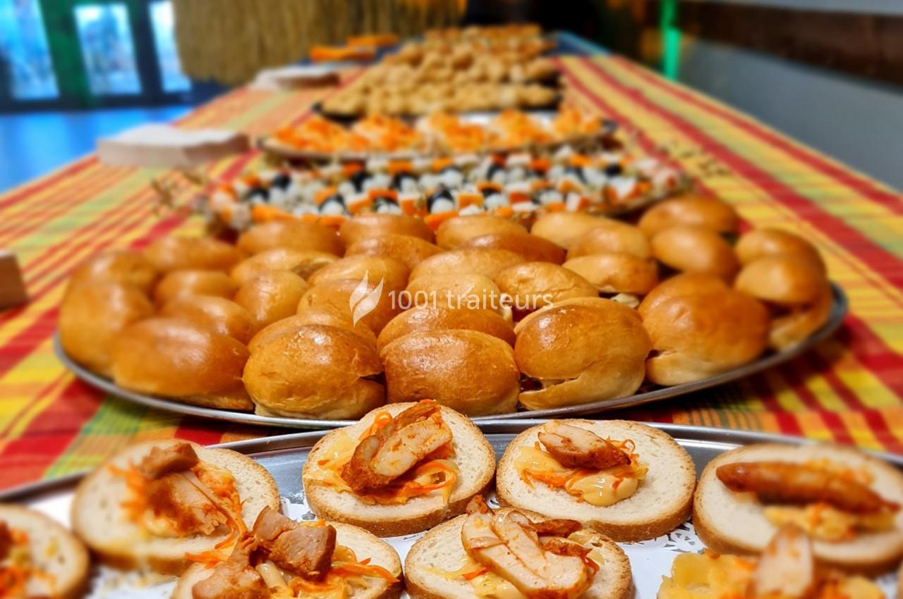 Plateaux de bouchées apéritives variées disposés sur une table recouverte d'une nappe colorée.