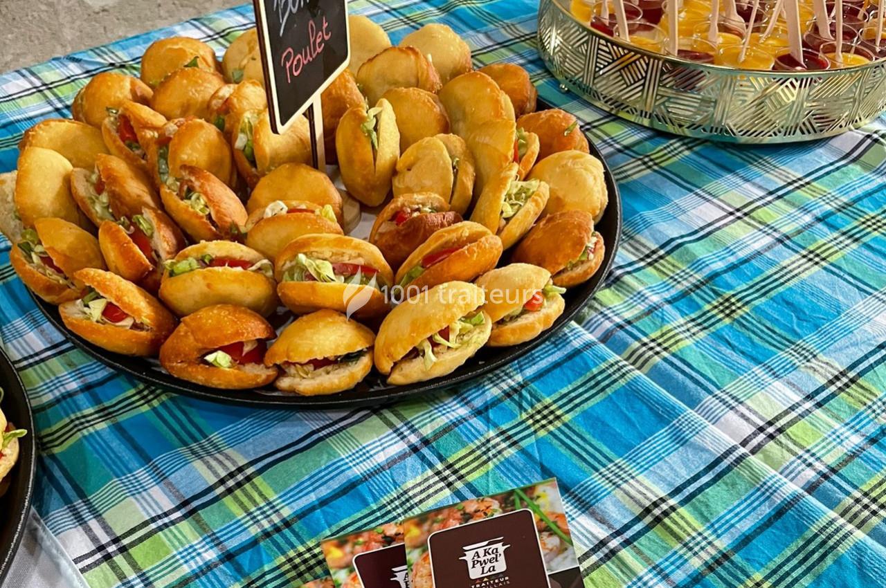 Plateau de mini-sandwichs garnis de légumes et de poulet, disposé sur une nappe à carreaux colorés.