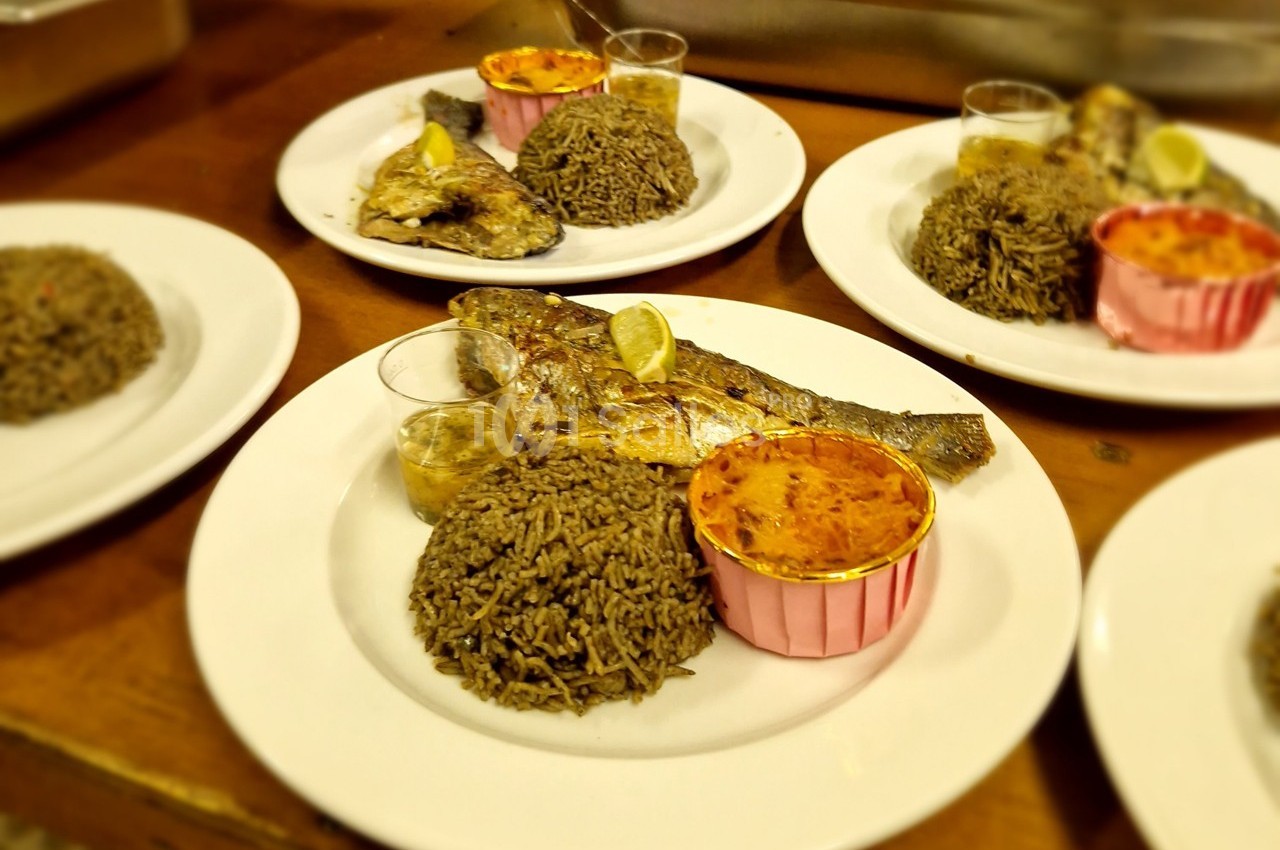 Assiettes servies avec du poisson grillé, du riz, une sauce en verrine et un accompagnement dans une coupelle rose.