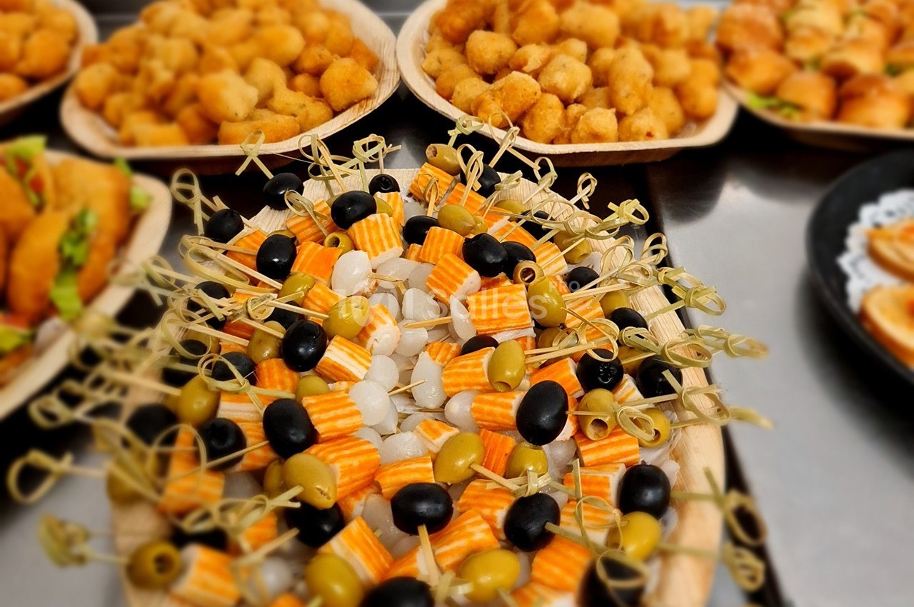 Plateau de brochettes apéritives avec olives, oignons et fromage, entouré de bouchées salées variées.