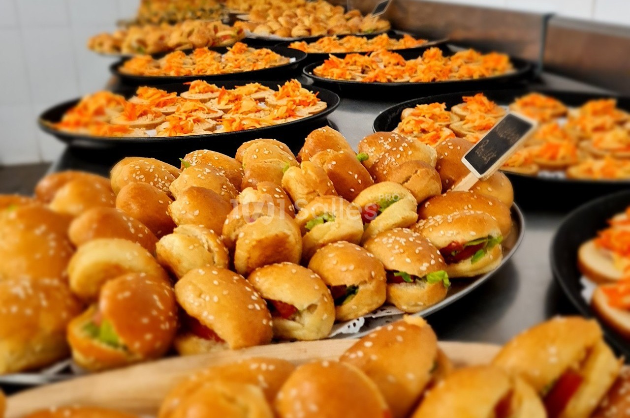 Plateaux garnis de mini-sandwichs, pizzas et amuse-bouches variés disposés sur une table dans un cadre traiteur.