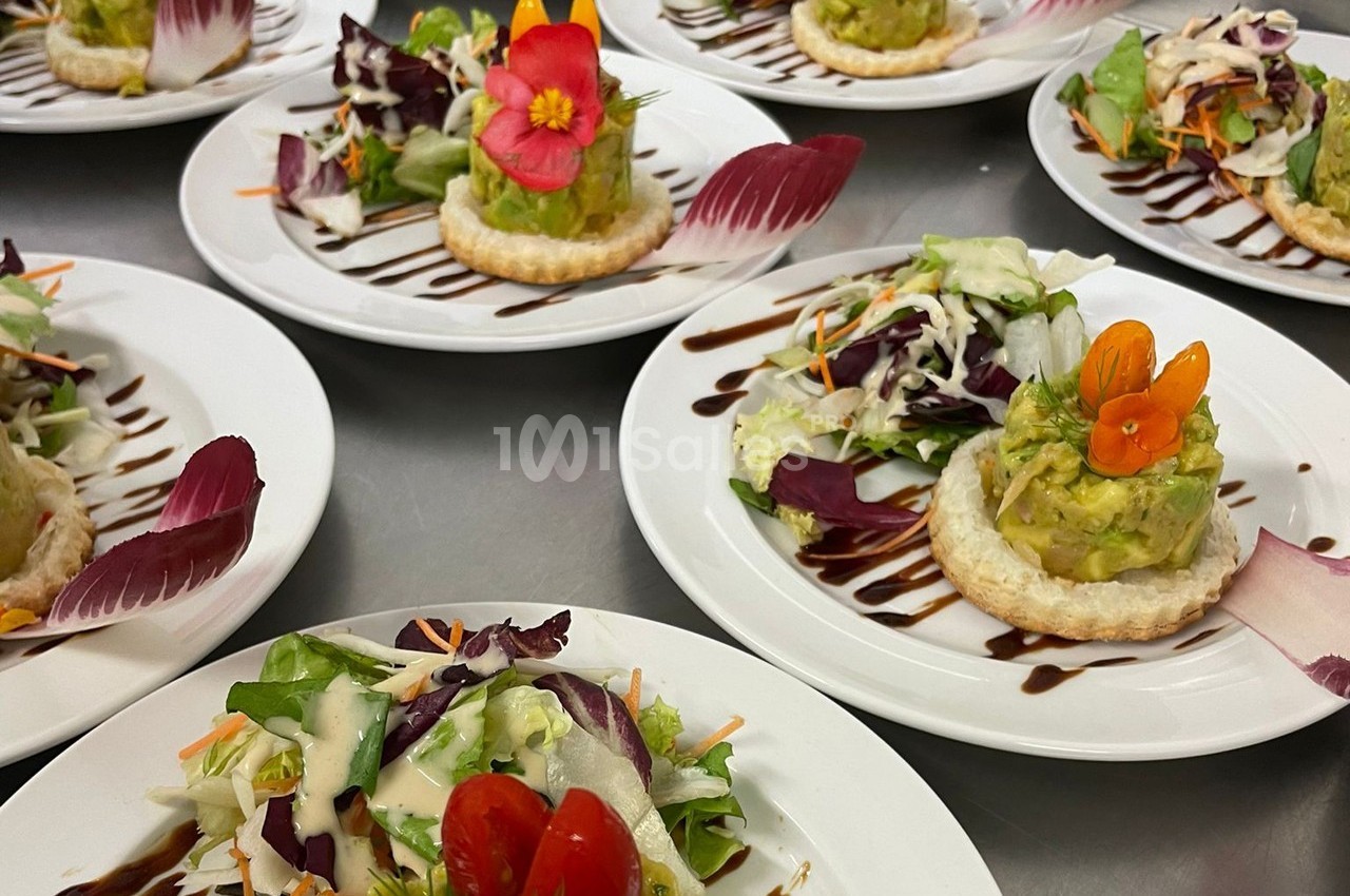 Assiettes garnies de salades colorées, tartares d'avocat sur pâte feuilletée et filet de sauce balsamique.