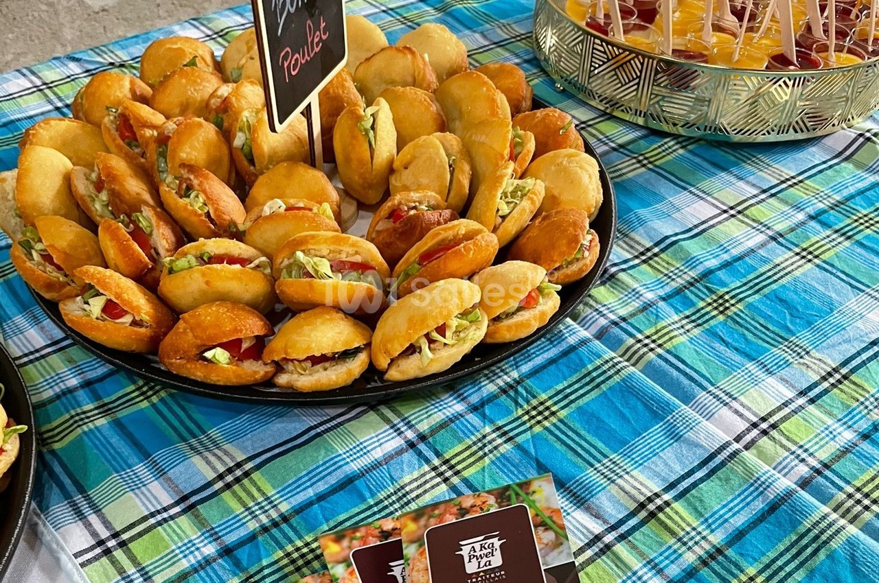 Plateau de mini-sandwichs garnis de légumes et de poulet, disposé sur une nappe à carreaux colorés.