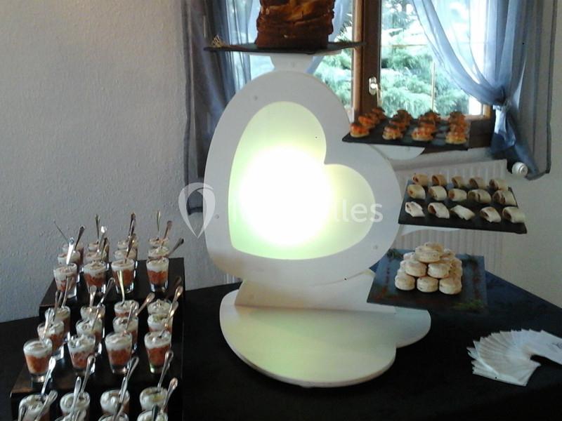 Présentoir en forme de cœur éclairé, avec verrines, mignardises et amuse-bouches disposés sur plusieurs niveaux.