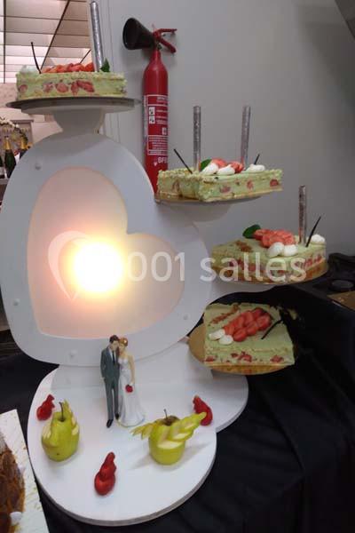 Pièce montée en forme de cœur avec des parts de gâteau décorées de fraises et une figurine de mariage.