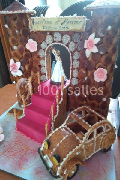 Pièce montée en choux représentant un château avec une mariée sur un escalier rose et une voiture en pâte à choux.