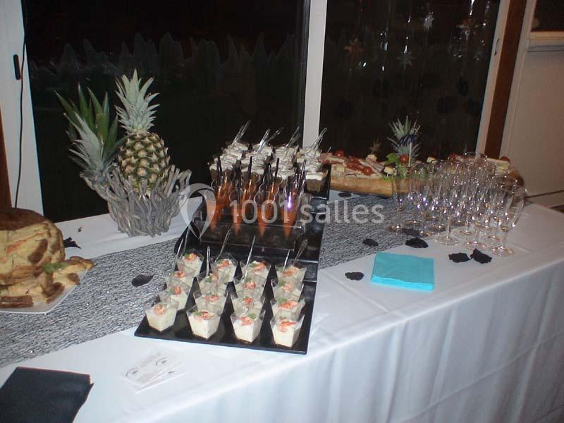 Buffet avec verrines, brochettes et verres disposés sur une table blanche décorée.
