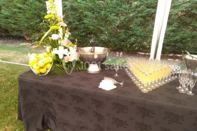 Table de buffet dressée en extérieur avec boissons, verrines, desserts et une pièce montée sur une nappe noire.