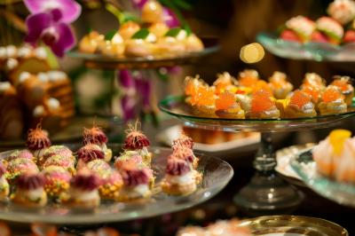 Un serveur portant un plateau avec des flûtes de champagne lors d'un événement en extérieur sous des arbres.