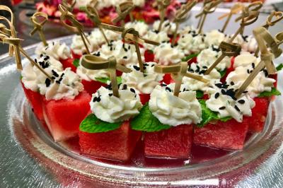 Un serveur portant un plateau avec des flûtes de champagne lors d'un événement en extérieur sous des arbres.