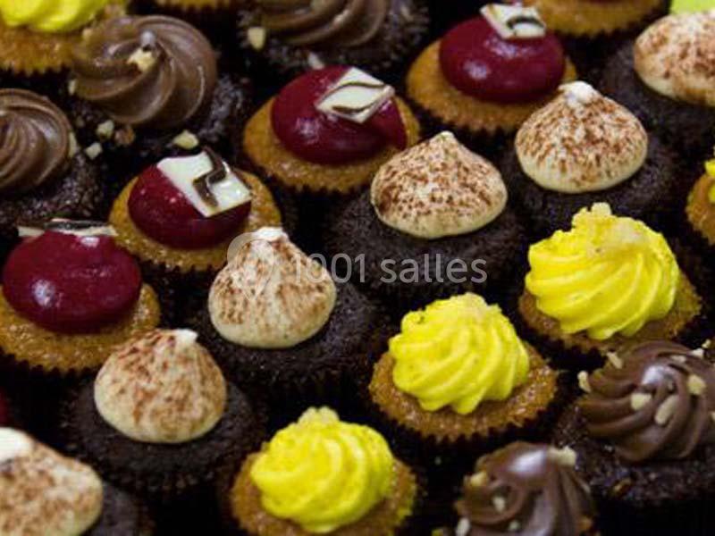 Assortiment de petits cupcakes décorés de glaçages colorés au chocolat, vanille, fruits rouges et citron.
