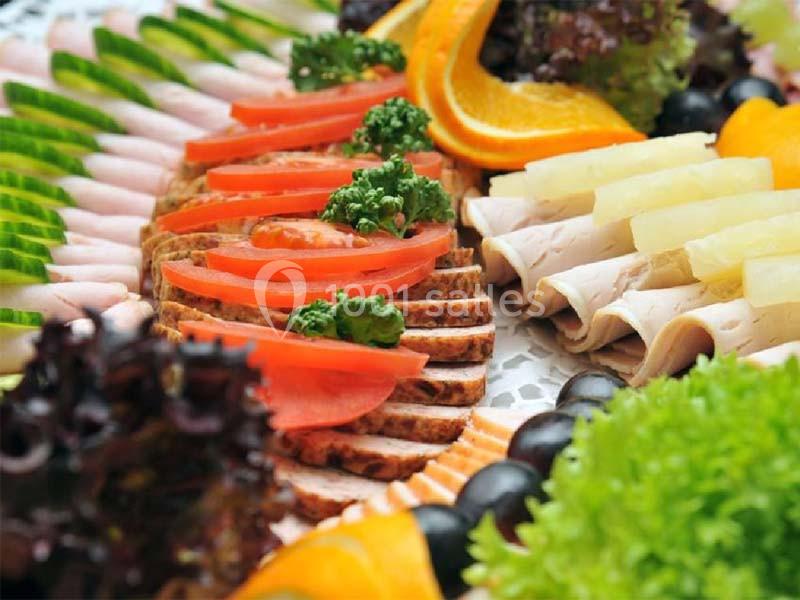 Plateau de charcuterie et légumes avec tranches de pain, tomates, concombres, salade, oranges et ananas.