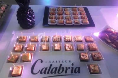 Centre de table floral avec roses et magnolias, bouteille de vin, numéro de table et décorations sur une nappe blanche.