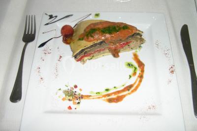 Centre de table floral avec roses et magnolias, bouteille de vin, numéro de table et décorations sur une nappe blanche.