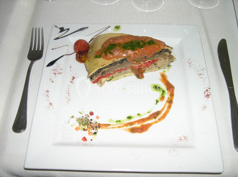 Part de lasagnes aux légumes grillés, servie avec une sauce tomate et une décoration soignée sur une assiette blanche.