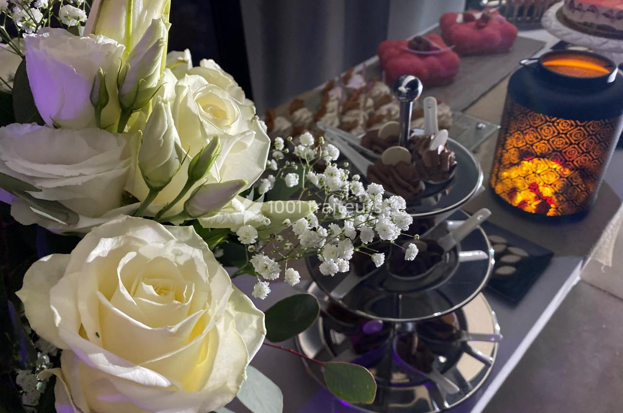 Bouquet de roses blanches et gypsophiles près d'un présentoir à desserts et d'une lanterne allumée.