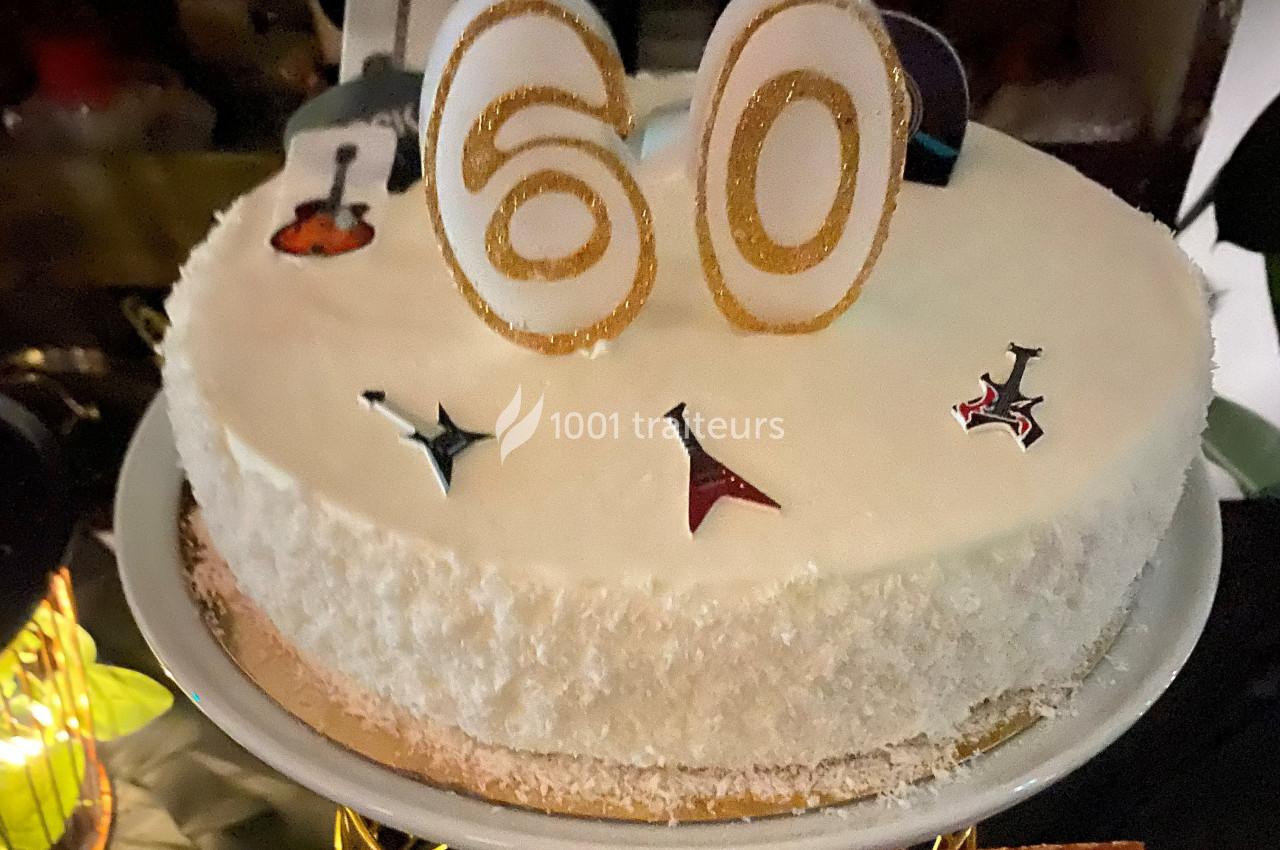 Gâteau blanc décoré pour un 60e anniversaire avec des bougies dorées et des motifs de guitares.