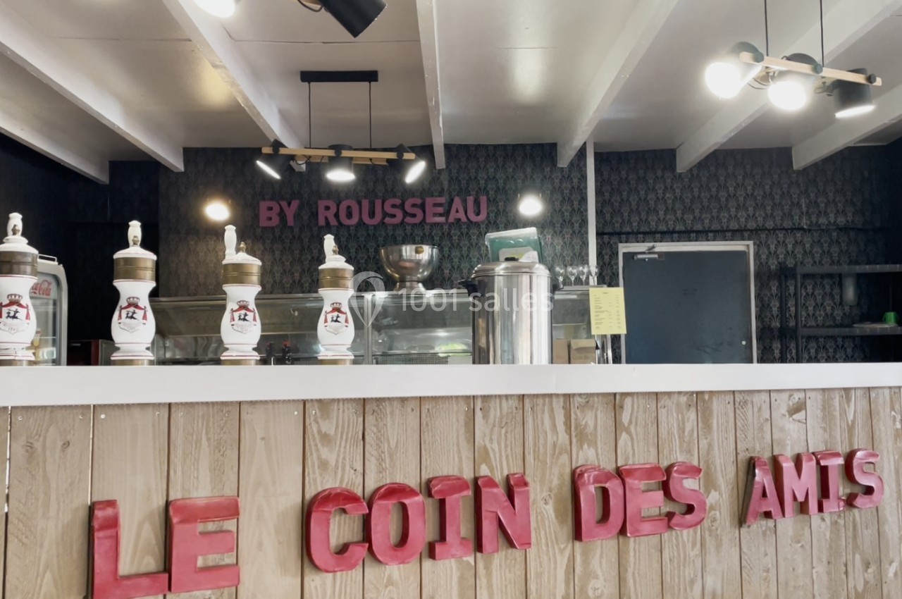 Comptoir en bois clair avec des machines à glace et une enseigne ’Le Coin des Amis’ en lettres rouges.