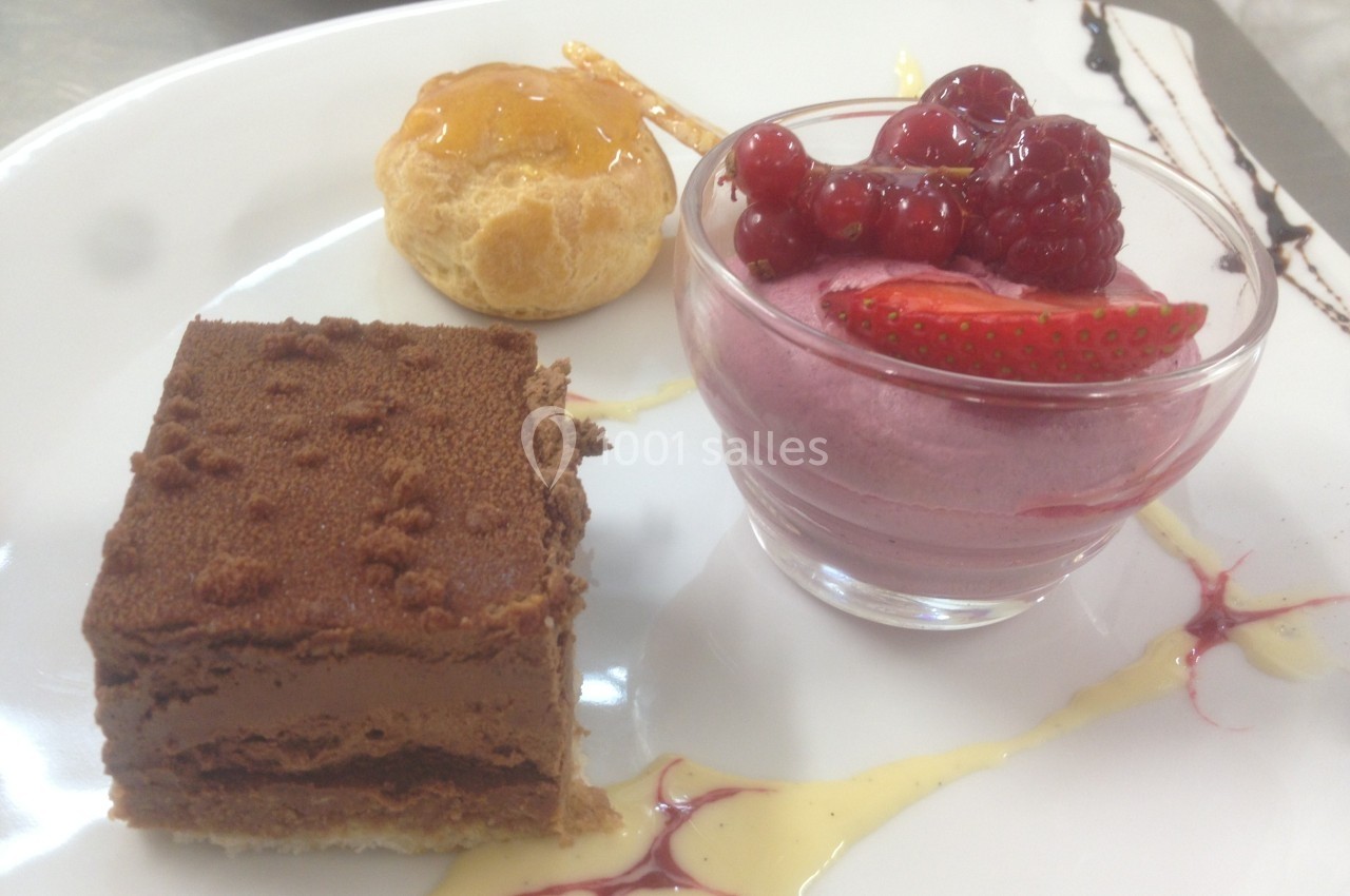 Assiette de desserts composée d'un gâteau au chocolat, d'une mousse aux fruits rouges et d'une chouquette glacée.