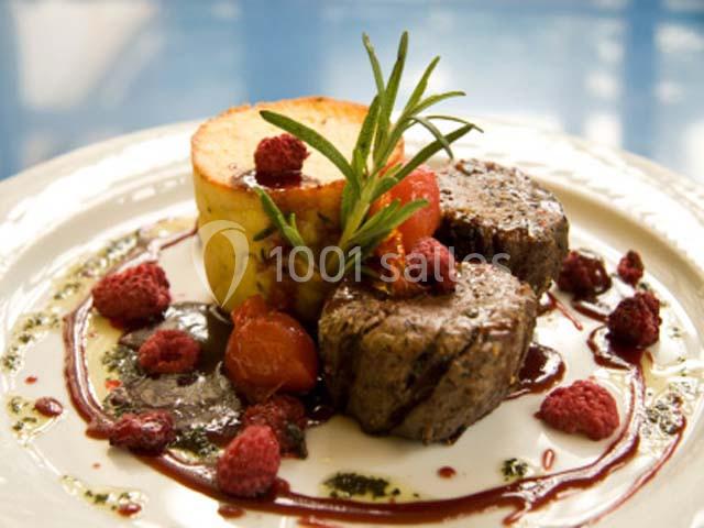 Assiette gastronomique avec médaillons de viande, purée gratinée, framboises, sauce et garniture de romarin.