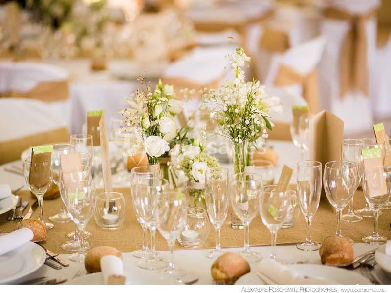 Traiteur Arsac (Gironde) - Domaine de Cordet #18 Table dressée avec nappes blanches, chemins de table en toile de jute, fleurs blanches et verres disposés pour un repas.