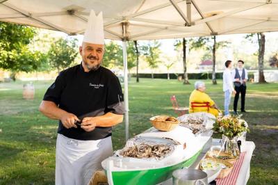 Miniature Traiteur Arsac (Gironde) - Domaine de Cordet #8 Un kiosque blanc au bord d'un étang avec une fontaine, entouré d'arbres et d'une réception en arrière-plan.