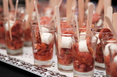 Un kiosque blanc au bord d'un étang avec une fontaine, entouré d'arbres et d'une réception en arrière-plan.