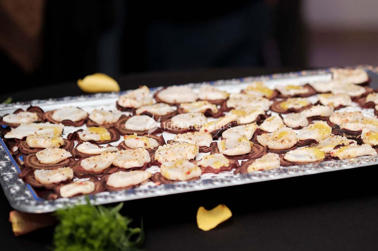 Plateau de bouchées apéritives garnies de crème et d'assaisonnements, présenté sur une table noire.