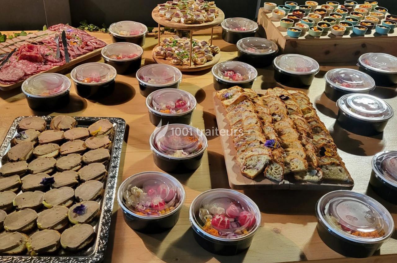 Buffet avec charcuterie, terrines, pains garnis et verrines colorées disposés sur une table en bois.