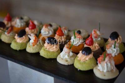 Plateau de canapés variés comprenant des bouchées salées et sucrées, disposées sur une table en inox.