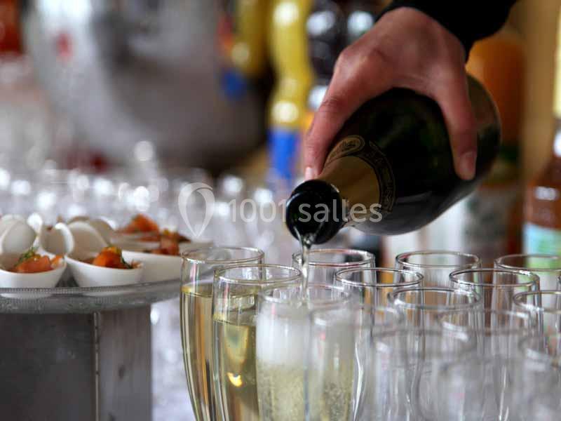 Une main verse du champagne dans des flûtes alignées, avec des amuse-bouches disposés à côté.