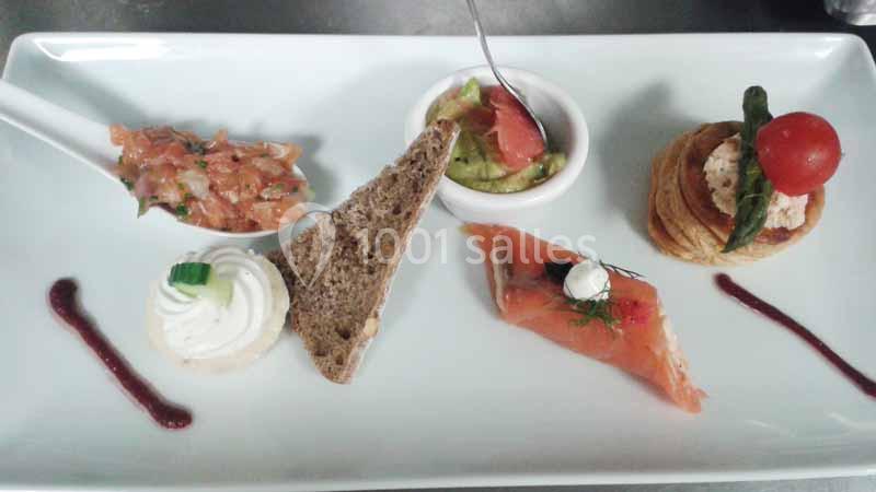 Assiette de dégustation avec saumon fumé, tartare, mousse, pain, avocat et garnitures décoratives.