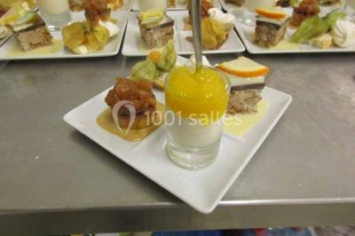 Plateau de canapés variés comprenant des bouchées salées et sucrées, disposées sur une table en inox.