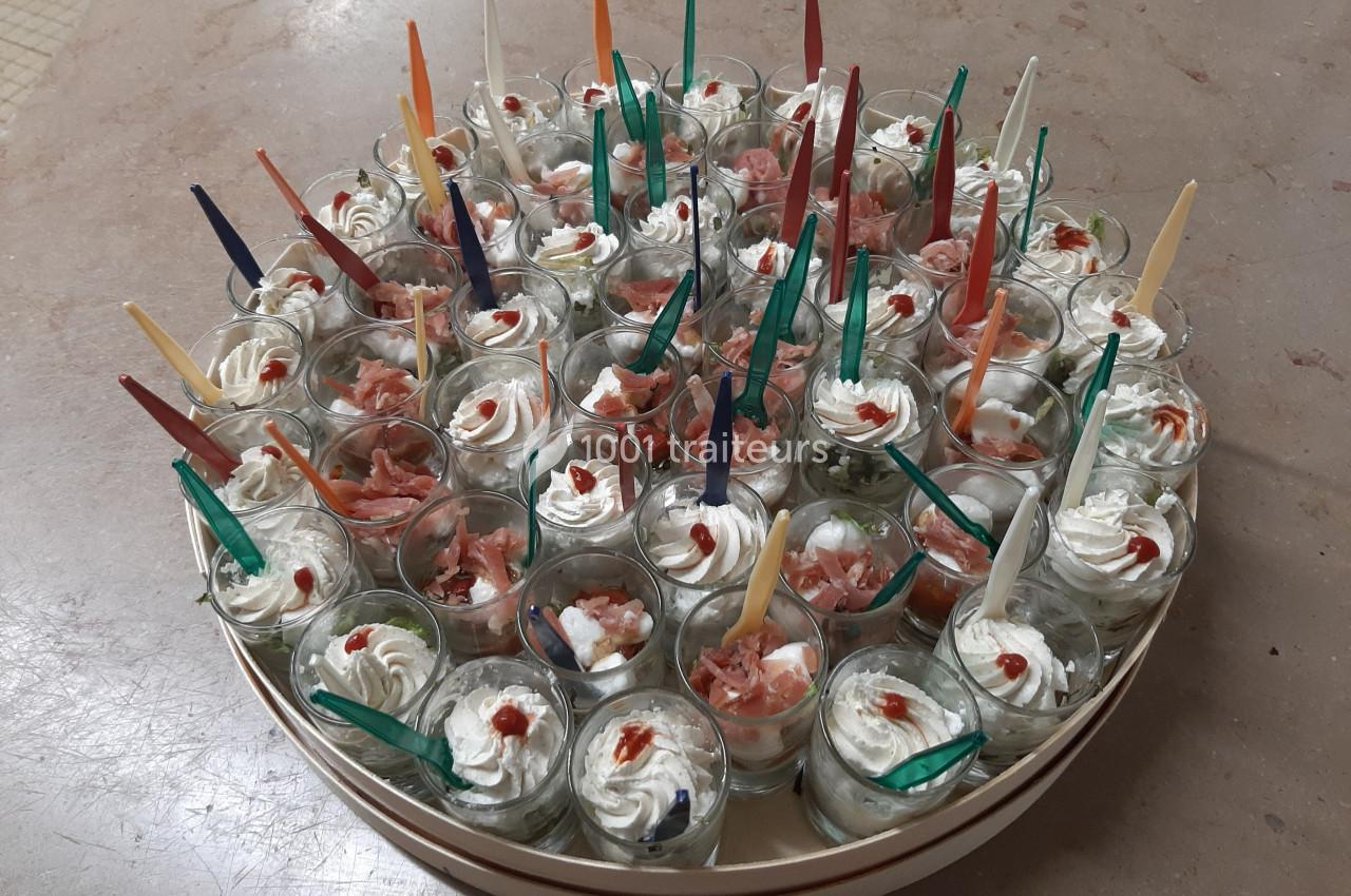 Plateau de verrines apéritives garnies de crème, saumon et décorées de petites cuillères colorées.