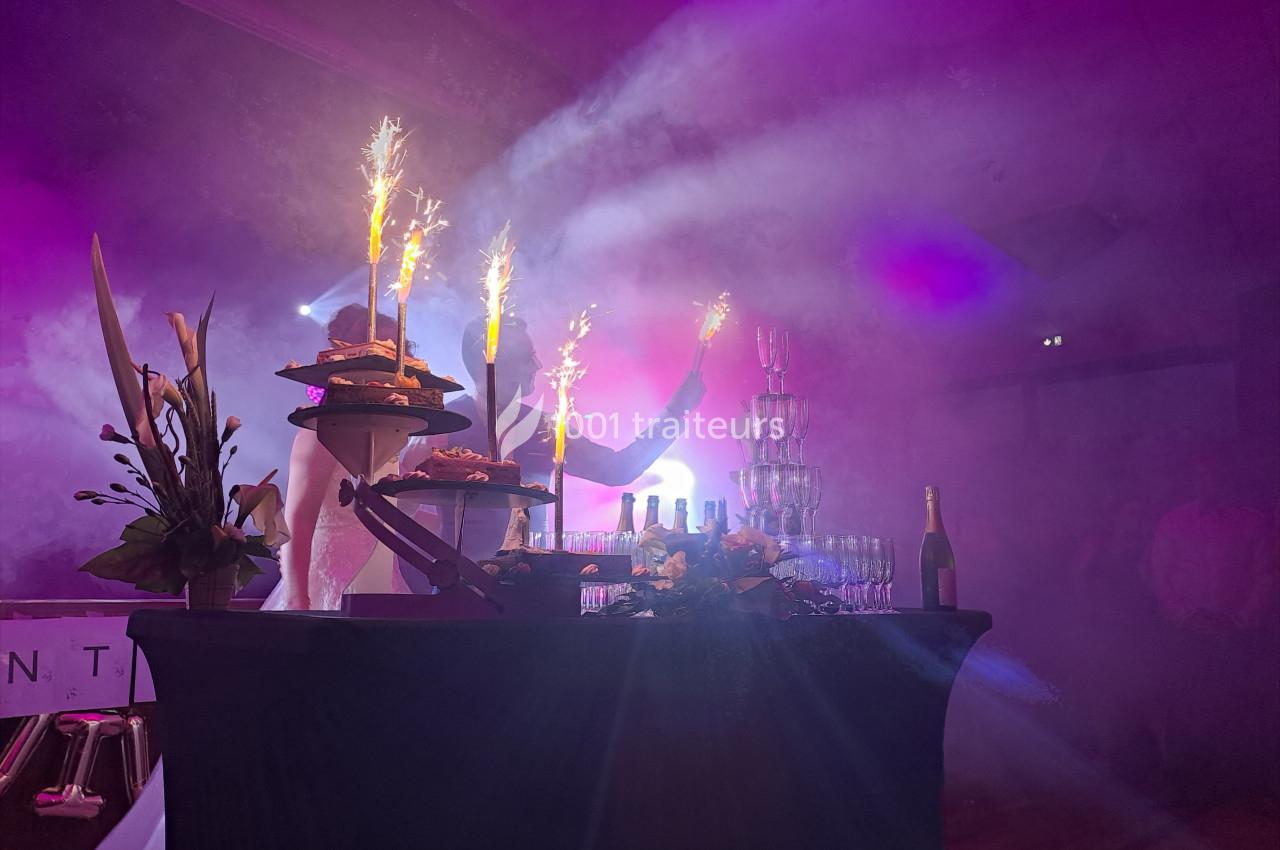 Table décorée avec des desserts, des fontaines de champagne et des cierges magiques allumés dans une ambiance festive.