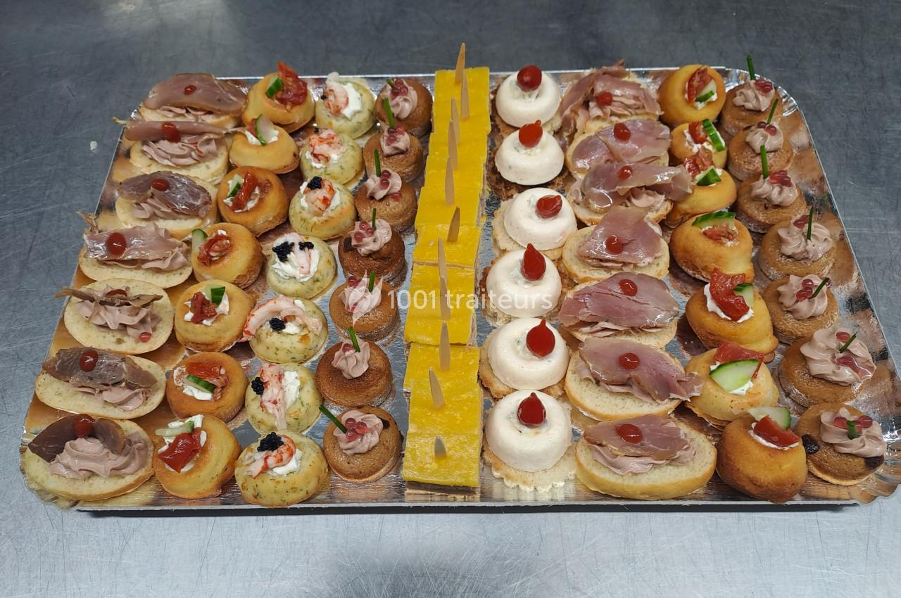 Plateau de canapés variés comprenant des bouchées salées et sucrées, disposées sur une table en inox.