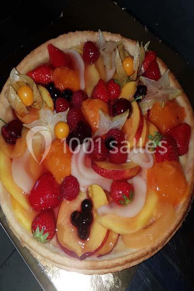 Tarte garnie de fruits variés tels que fraises, pêches, framboises, groseilles et physalis sur une pâte dorée.