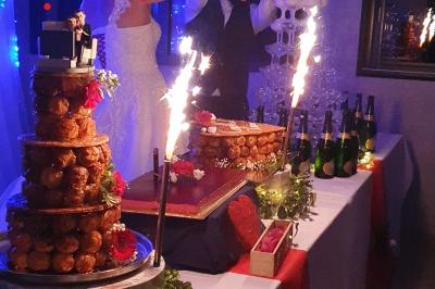 Miniature Traiteur Limas (Rhône) - Marc et Sophie Traiteur Cuisine & Services #26 Tour de choux décorée avec des fleurs et des étincelles, entourée de desserts sur une table de réception.