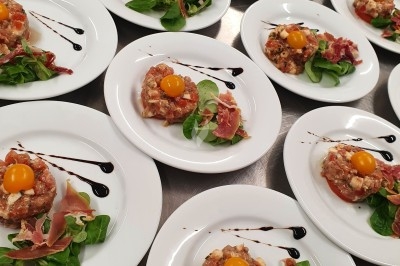 Un camion de traiteur avec des illustrations culinaires, accompagné de personnes préparant et servant des plats.